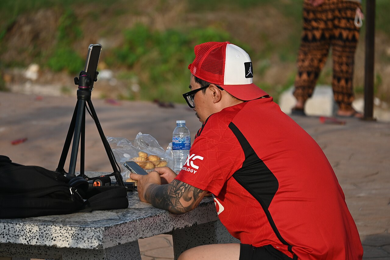 Person checking their balance on a phone next to a laptop on their desk