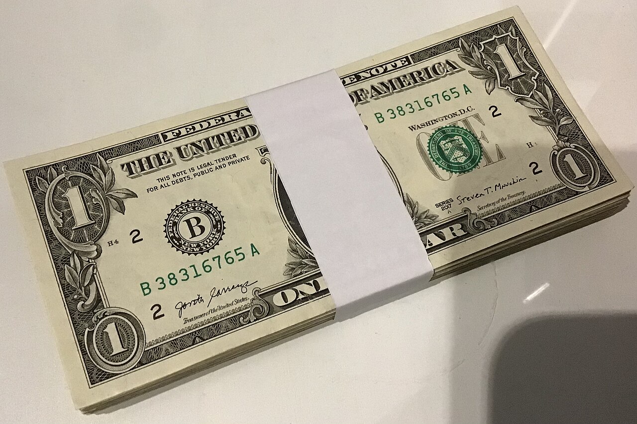 Dollar bills next to a smartphone, the idea behind the USDT and USDC stablecoins